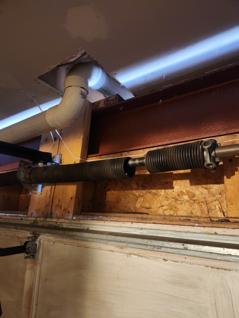 Broken garage door torsion spring snapped in two on the metal shaft — Ottawa