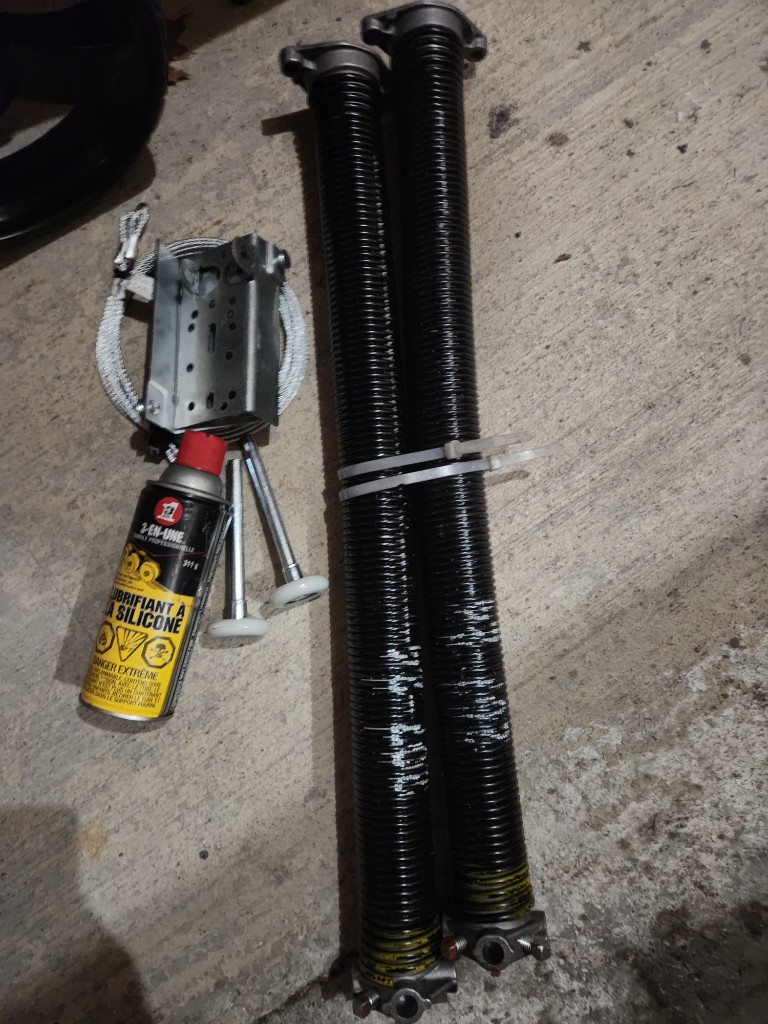 New torsion springs, rollers, and hardware ready for garage door spring replacement